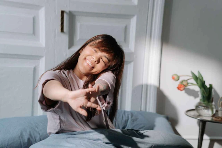 Anak tersenyum saat bangun tidur sebagai langkah awal cara membangun rutinitas pagi anak sekolah yang tenang.