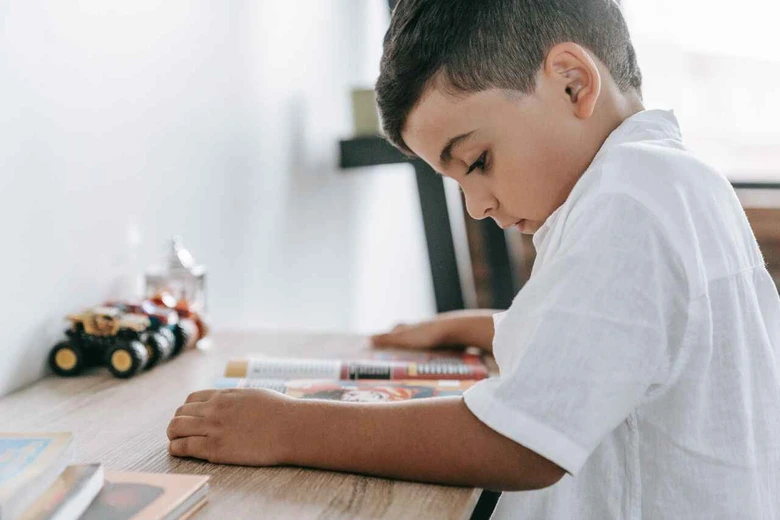 Anak sedang fokus membaca buku sebagai langkah mengatasi learning loss anak setelah libur panjang.