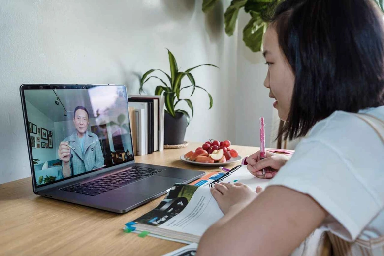 Siswa tersenyum sambil menatap layar laptop, merepresentasikan fleksibilitas antara sesi daring dan les privat awal tahun ajaran guru ke rumah.