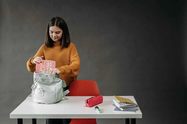 Menyiapkan buku pelajaran ke dalam tas bagian dari cara membangun rutinitas pagi anak sekolah.