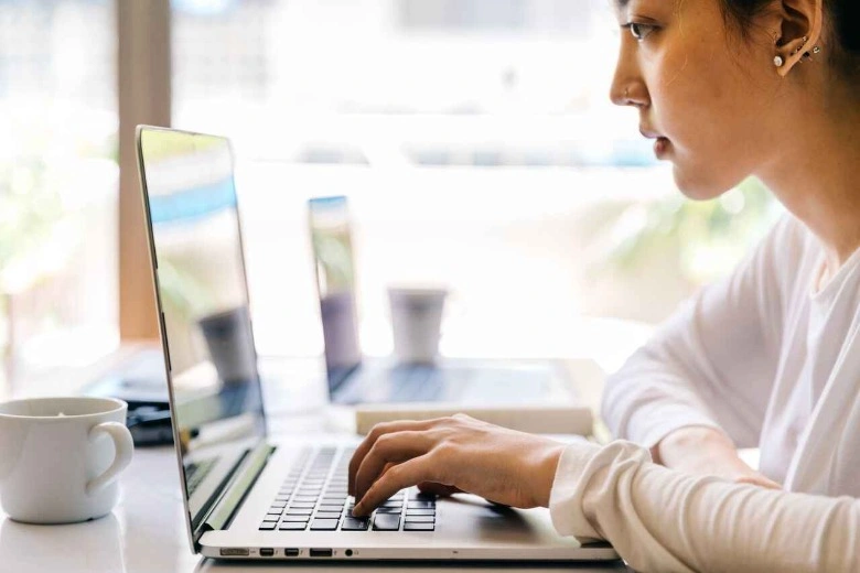 Seorang siswa tersenyum sambil melihat layar laptop, bersiap mengikuti les privat online awal tahun ajaran baru.